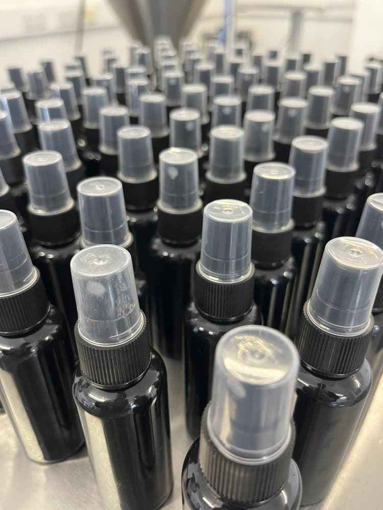 Retail spray bottles staged after a fragrance or personal-care fill.