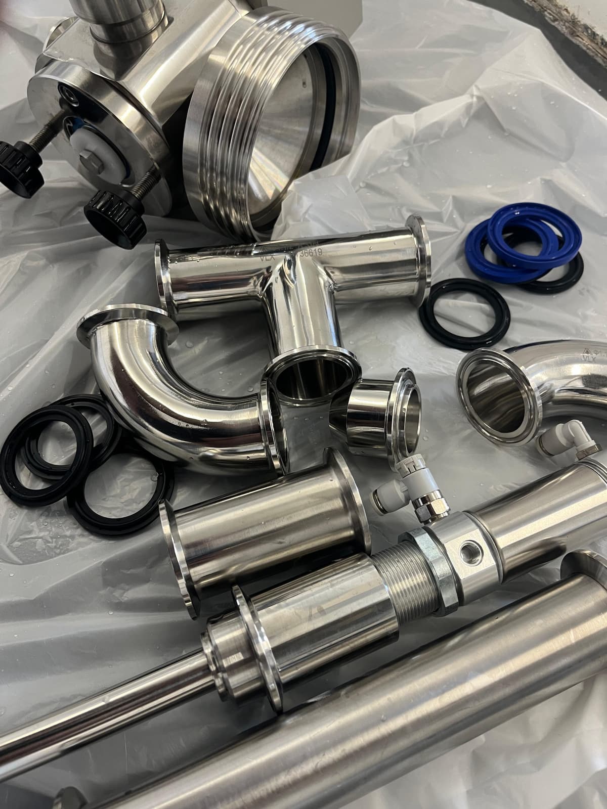 Stainless fill-line parts laid out for mechanical strip-down and deep clean between runs.