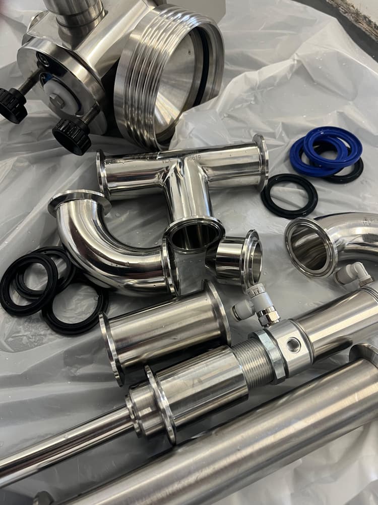 Stainless mixing parts laid out during a post-batch hygiene strip-down.
